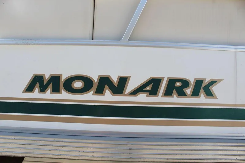 Slide: The Image of 1997 Monark Pontoon boat logo with green and gold accents. - 21