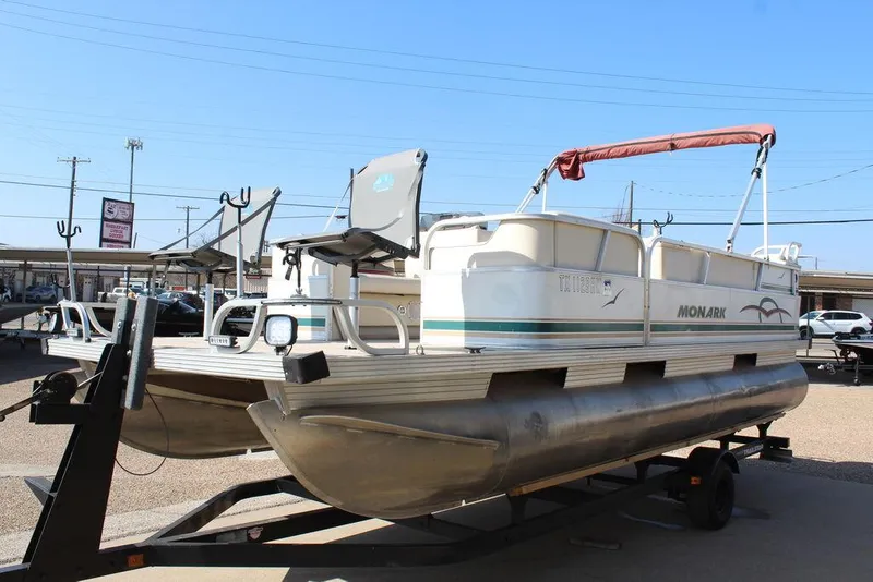 Slide: The Image of 1997 Monark Pontoon boat on trailer, featuring a red canopy and spacious deck. - 6