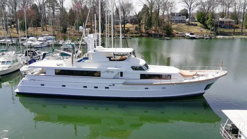 The Image of 1984 Broward 100 yacht docked in a serene marina setting. - 0