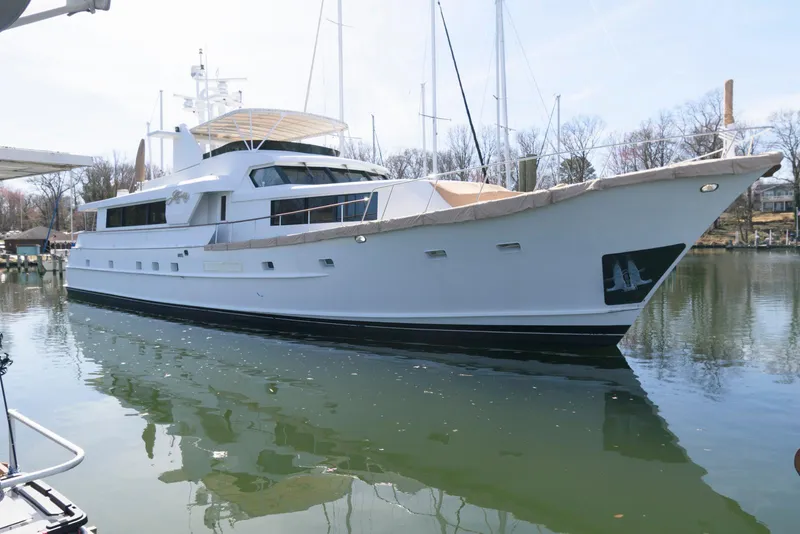 Slide: The Image of Luxury Broward 100 yacht from 1984 docked on calm water. - 1