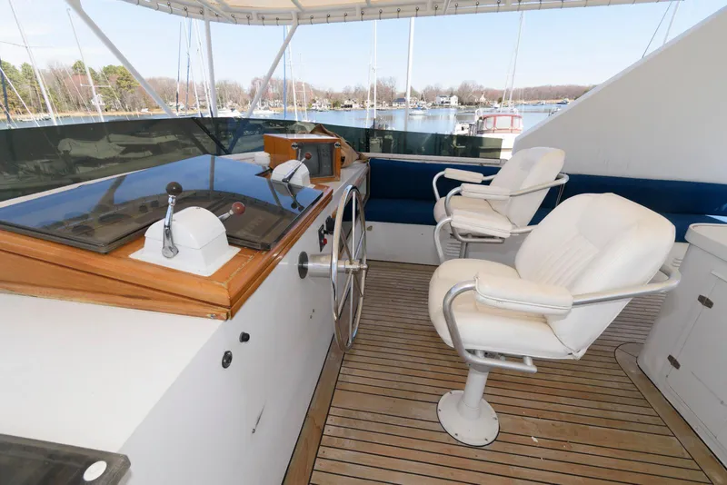 Slide: The Image of Helm of 1984 Broward 100 yacht with white captain chairs and wooden deck. - 13