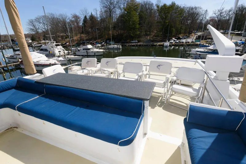 Slide: The Image of Upper deck of 1984 Broward 100 yacht with blue seating and marina view. - 16