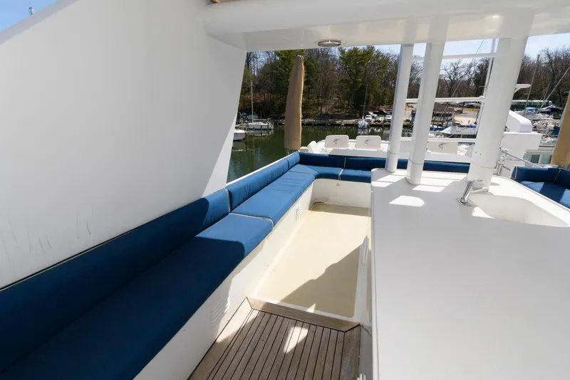 Slide: The Image of Outdoor seating area on a 1984 Broward 100 yacht with blue cushions and wooden deck. - 17