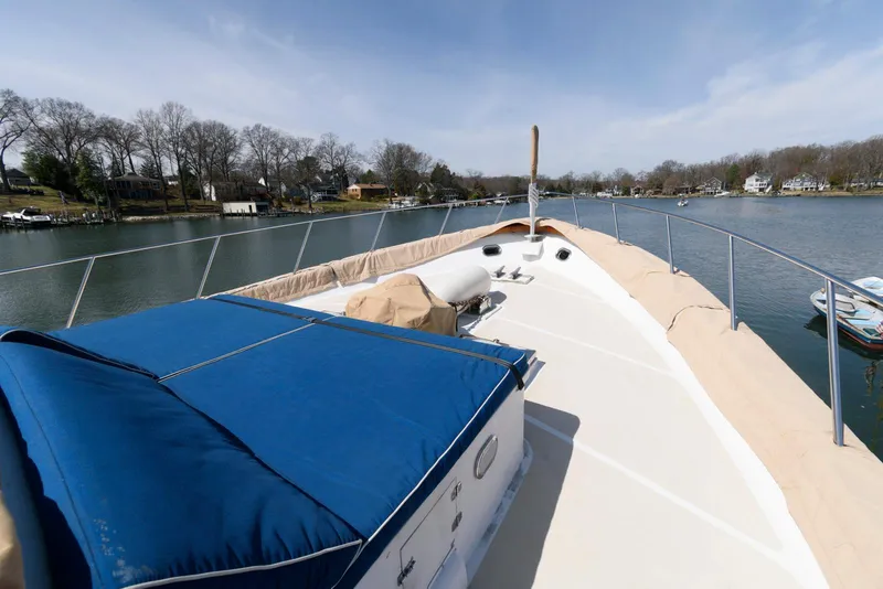 Slide: The Image of 1984 Broward 100 yacht deck with blue cover, cruising on a serene river. - 24