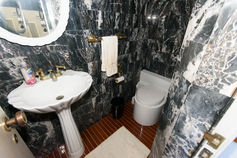 Slide: The Image of Luxurious bathroom with marble walls, pedestal sink, and modern toilet on a Broward 100 yacht. - 40