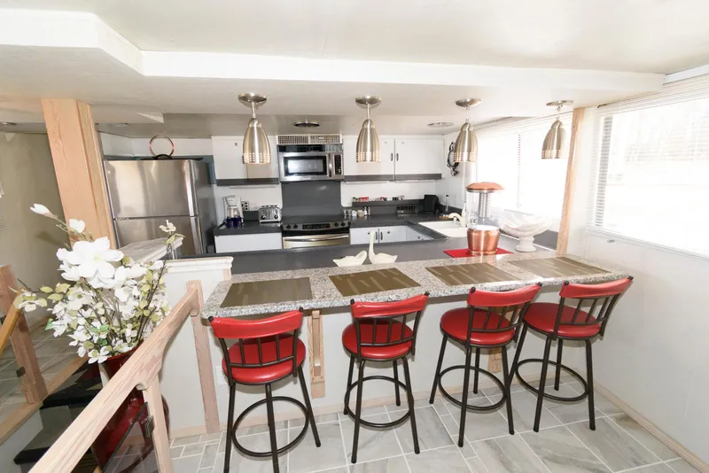 Slide: The Image of Modern kitchen on 1984 Broward 100 yacht with red bar stools and stainless steel appliances. - 42