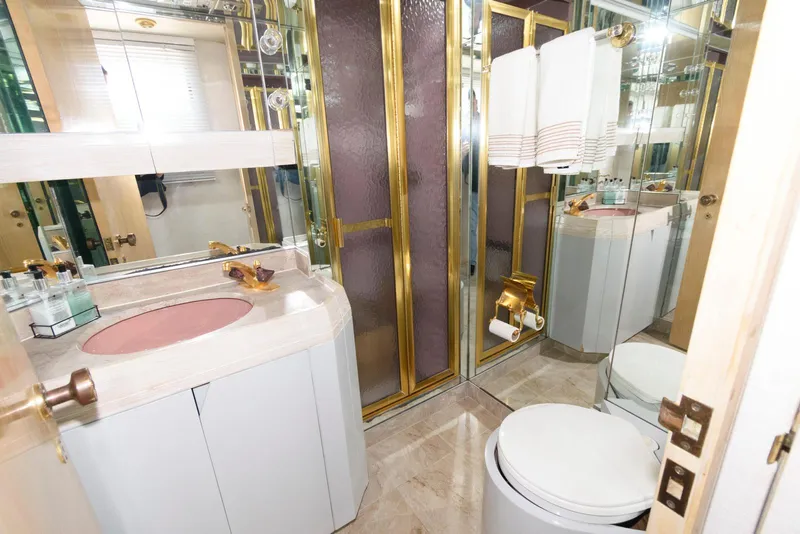 Slide: The Image of Luxurious 1984 Broward 100 yacht bathroom with gold accents and pink sink. - 45