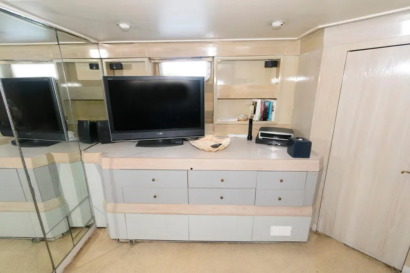 Slide: The Image of Luxurious interior of 1984 Broward 100 yacht with TV, mirrored wall, and modern decor. - 49