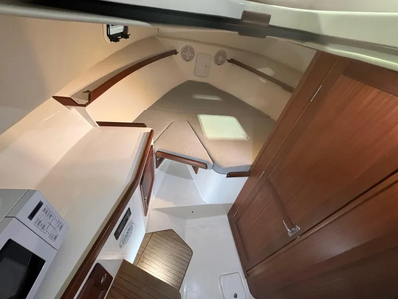 Slide: The Image of 2025 NorthCoast 315 HT cabin interior with wood accents and compact kitchen area. - 13