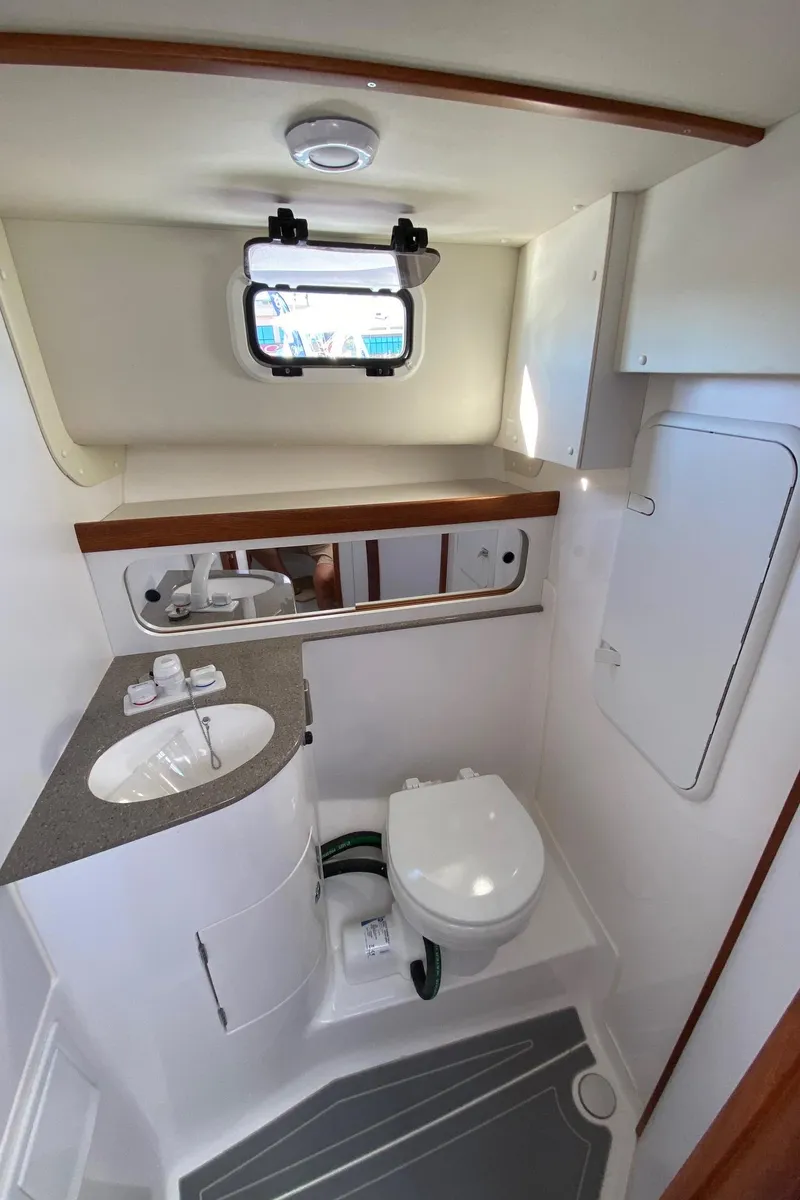 Slide: The Image of 2025 NorthCoast 315 HT boat bathroom with sink, toilet, and window. - 5