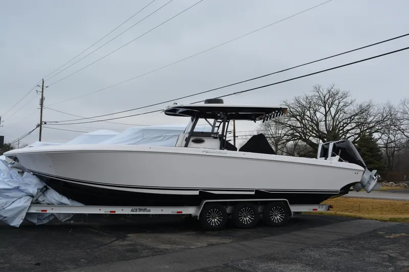 The Image of 2025 Fountain 34 CC boat on trailer, parked outdoors, overcast sky. - 0