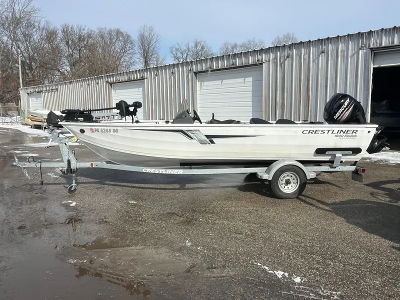 The Image of 2020 Crestliner 1800 Kodiak SC boat on trailer, parked outside metal building. - 0