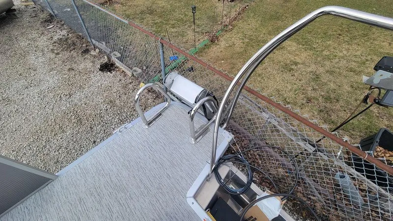 Slide: The Image of 2025 Bennington S Swingback 22 SSB boat deck with ladder and railing, near a fence. - 18