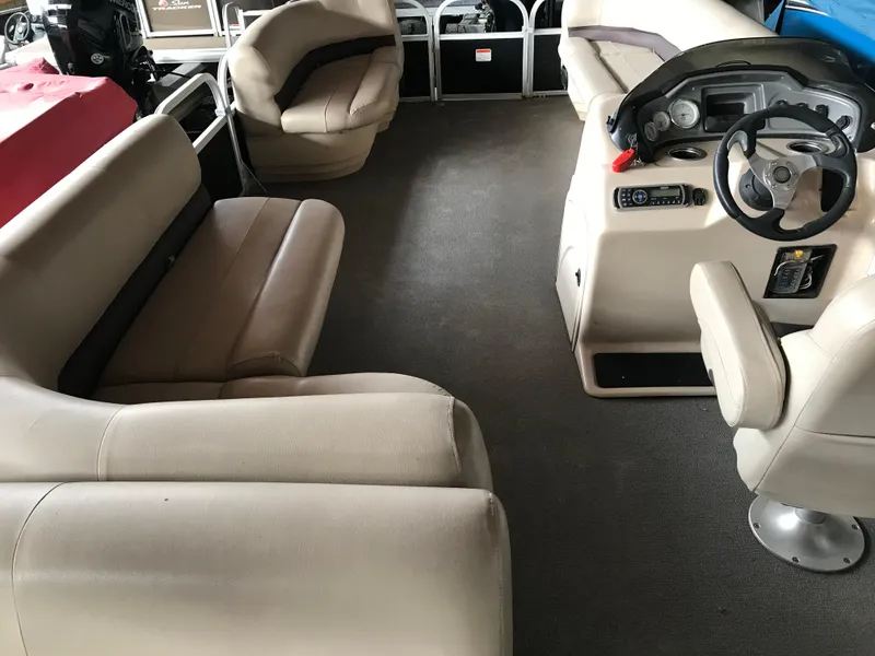 Slide: The Image of 2017 Sun Tracker Party Barge 22 DLX interior with beige seating and steering console. - 13