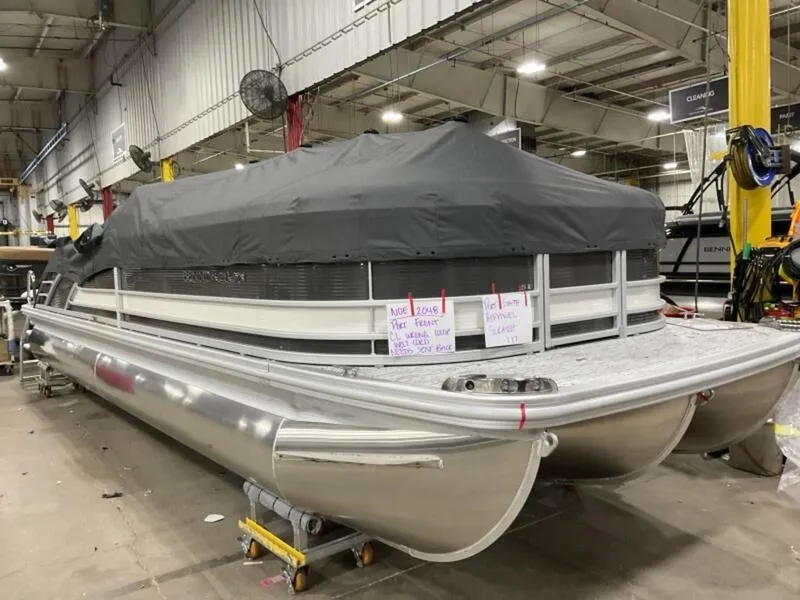 Slide: The Image of 2025 Bennington R Swingback 25 RSB pontoon boat in a warehouse, covered with a tarp. - 11