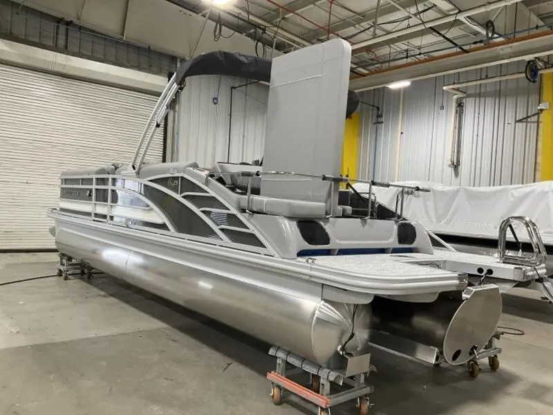 Slide: The Image of 2025 Bennington R Swingback 25 RSB pontoon boat in a warehouse setting. - 12