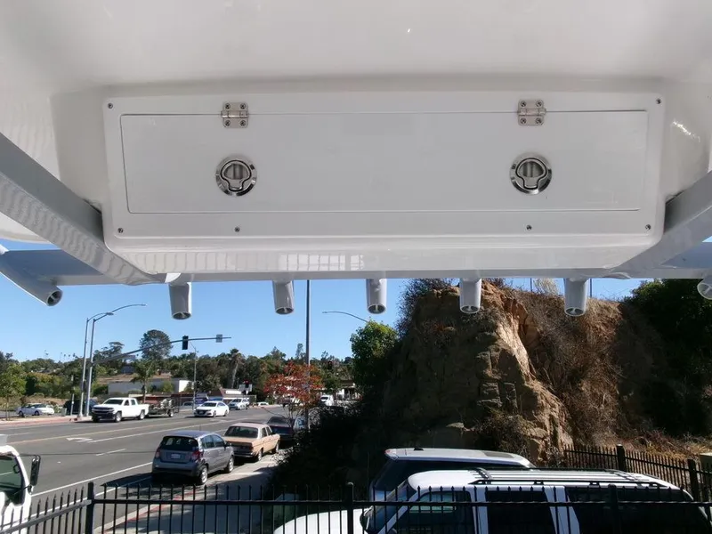 Slide: The Image of 2025 Sea Fox 248 Commander boat storage compartment with rod holders, parked near a road. - 22