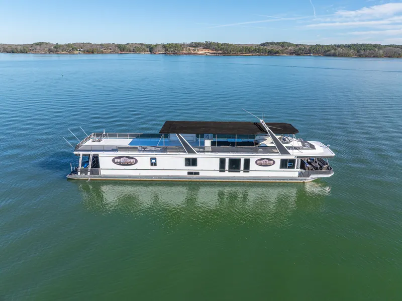 Slide: The Image of 1998 Stardust Cruisers Custom Luxury Houseboat on serene lake under clear blue sky. - 10