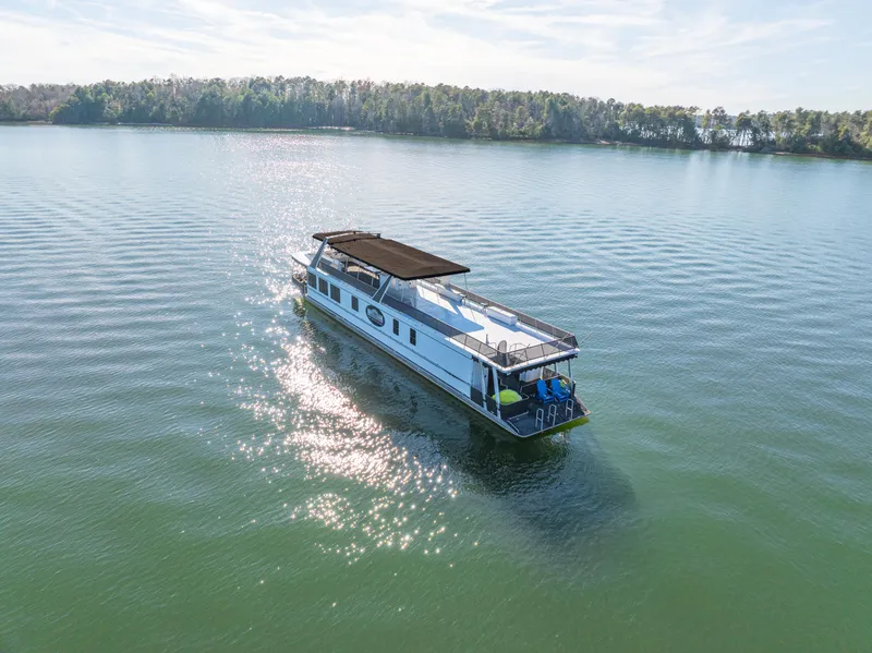 Slide: The Image of 1998 Stardust Cruisers Custom Luxury Houseboat on serene lake with forested shoreline. - 13