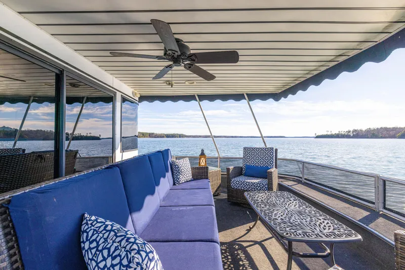 Slide: The Image of Luxury houseboat deck with blue seating, ceiling fan, and scenic lake view. Stardust Cruisers 1998 model. - 15