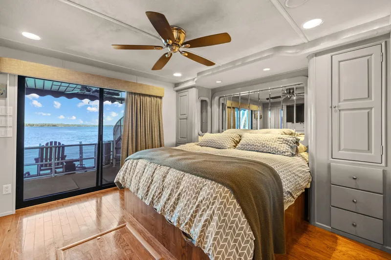 Slide: The Image of Luxurious 1998 Stardust Cruisers houseboat bedroom with lake view, ceiling fan, and cozy bedding. - 31
