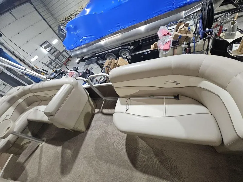 Slide: The Image of 2012 Bennington 20SL pontoon boat interior with beige seating in a workshop. - 12