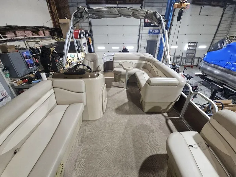 Slide: The Image of 2012 Bennington 20SL pontoon boat interior with beige seating in a garage setting. - 13