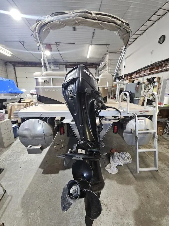 Slide: The Image of 2012 Bennington 20SL pontoon boat with outboard motor in a garage setting. - 6