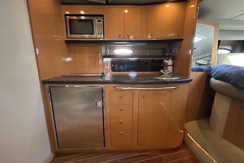 Slide: The Image of 2006 Chaparral Signature 350 yacht interior kitchen with microwave, fridge, and wooden cabinetry. - 23