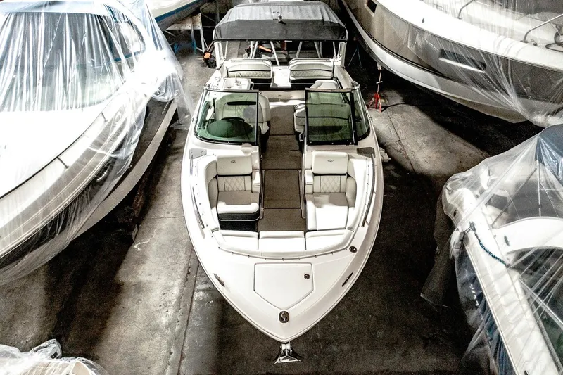Slide: The Image of 2021 Regal 2800 Bowrider boat in storage, surrounded by covered vessels. - 12