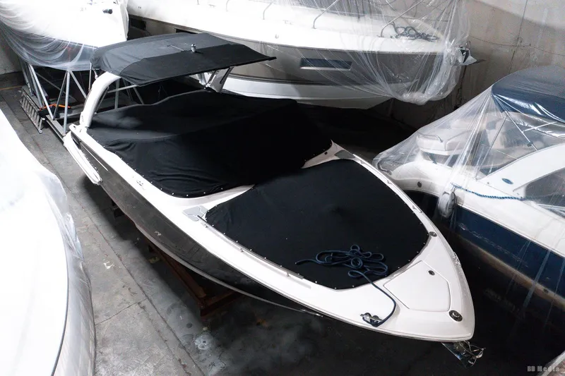 Slide: The Image of 2021 Regal 2800 Bowrider boat in storage, covered with black tarps. - 14