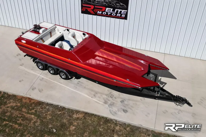 Slide: The Image of Red 1998 Warlock 28 SXT speedboat on trailer, parked outside RP Elite Motors. - 11