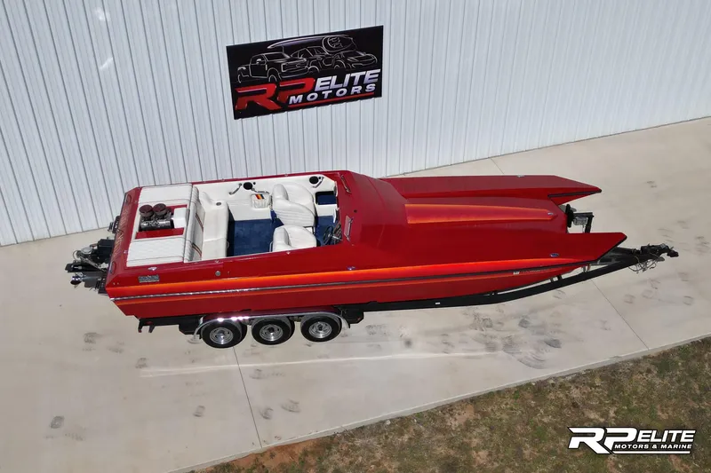 Slide: The Image of Red 1998 Warlock 28 SXT speedboat parked outside RP Elite Motors building. - 13