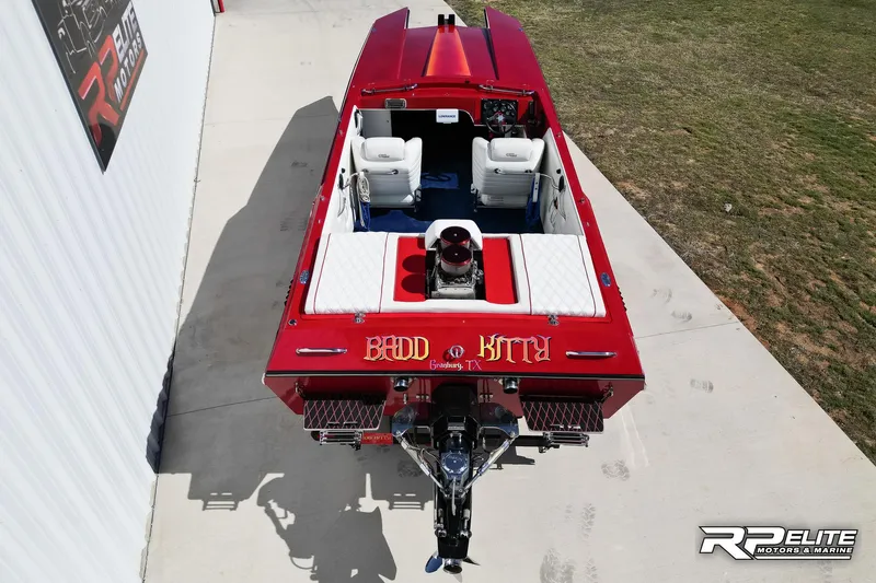 Slide: The Image of 1998 Warlock 28 SXT boat, red exterior, "Badd Kitty" text, parked on concrete. - 18