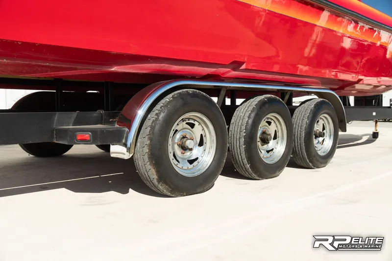 Slide: The Image of 1998 Warlock 28 SXT boat on a triple-axle trailer, red hull visible. - 22