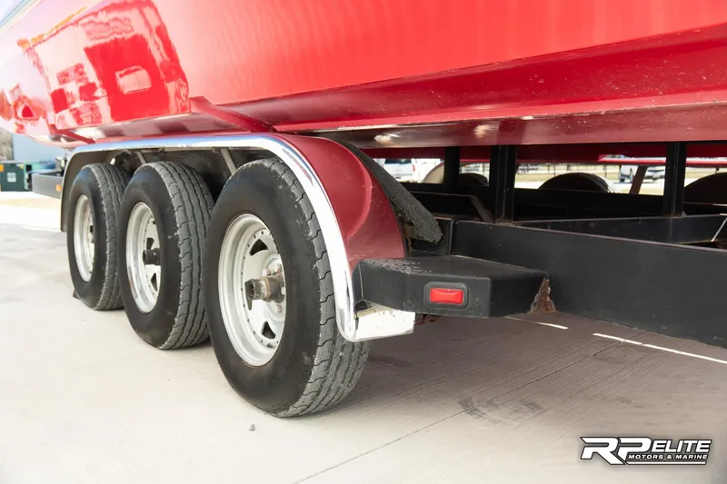 Slide: The Image of Red 1998 Warlock 28 SXT boat on a triple-axle trailer. - 36