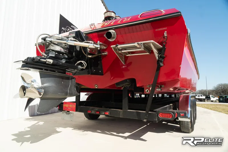 Slide: The Image of Red 1998 Warlock 28 SXT boat on trailer, rear view, showing engine and propeller. - 46