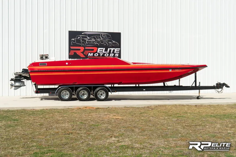 Slide: The Image of 1998 Warlock 28 SXT speedboat in red on a trailer, displayed at RP Elite Motors. - 9