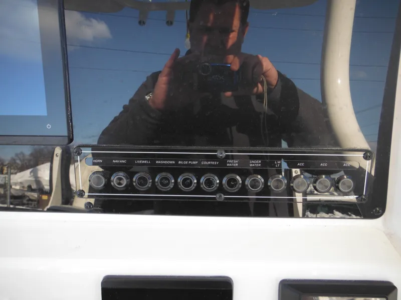 Slide: The Image of Control panel of 2025 Tidewater 232 LXF boat with various switches and reflections. - 48