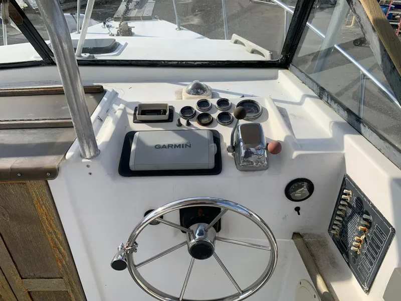 Slide: The Image of Boat dashboard with Garmin GPS, steering wheel, and controls on a 1987 Nauset 249 model. - 3