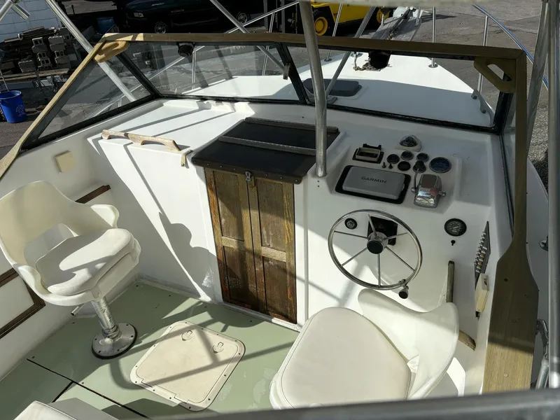 Slide: The Image of 1987 Nauset 249 boat cockpit with steering wheel, gauges, and white seating. - 7