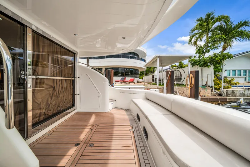 Slide: The Image of Luxurious 2002 Princess 61 yacht deck with seating, docked near modern waterfront homes. - 15