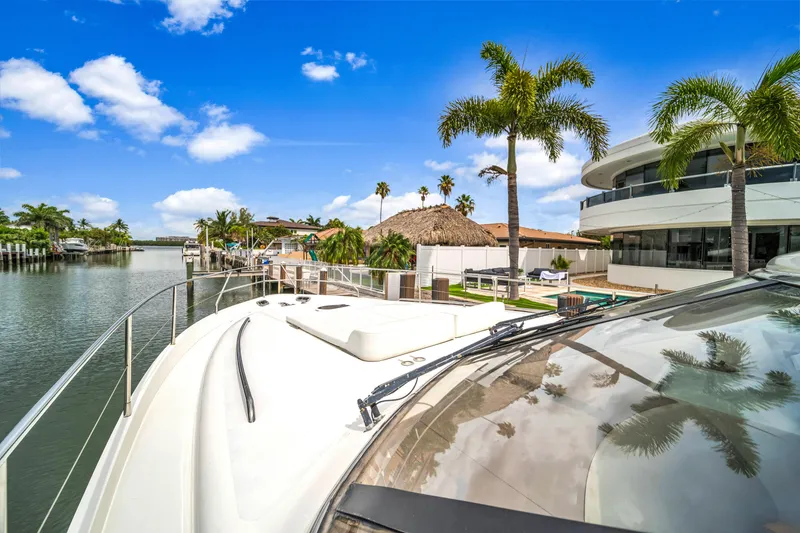 Slide: The Image of Luxury yacht docked by waterfront villa with palm trees, clear skies, and serene waterway. - 18