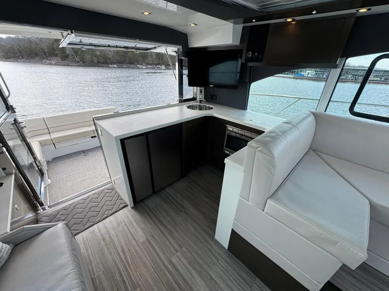 Slide: The Image of 2017 Cruisers Yachts 45 Cantius interior with modern kitchen and seating, overlooking water. - 10