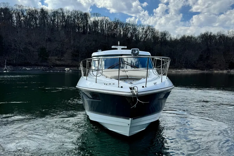 Slide: The Image of 2017 Cruisers Yachts 45 Cantius on a serene lake with wooded shoreline. - 2