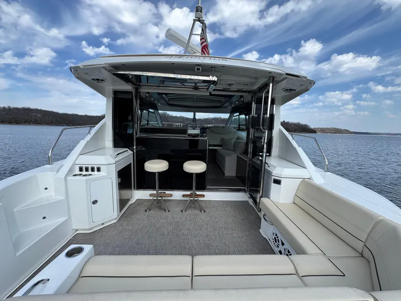 Slide: The Image of 2017 Cruisers Yachts 45 Cantius, spacious deck with seating, on a serene lake. - 6