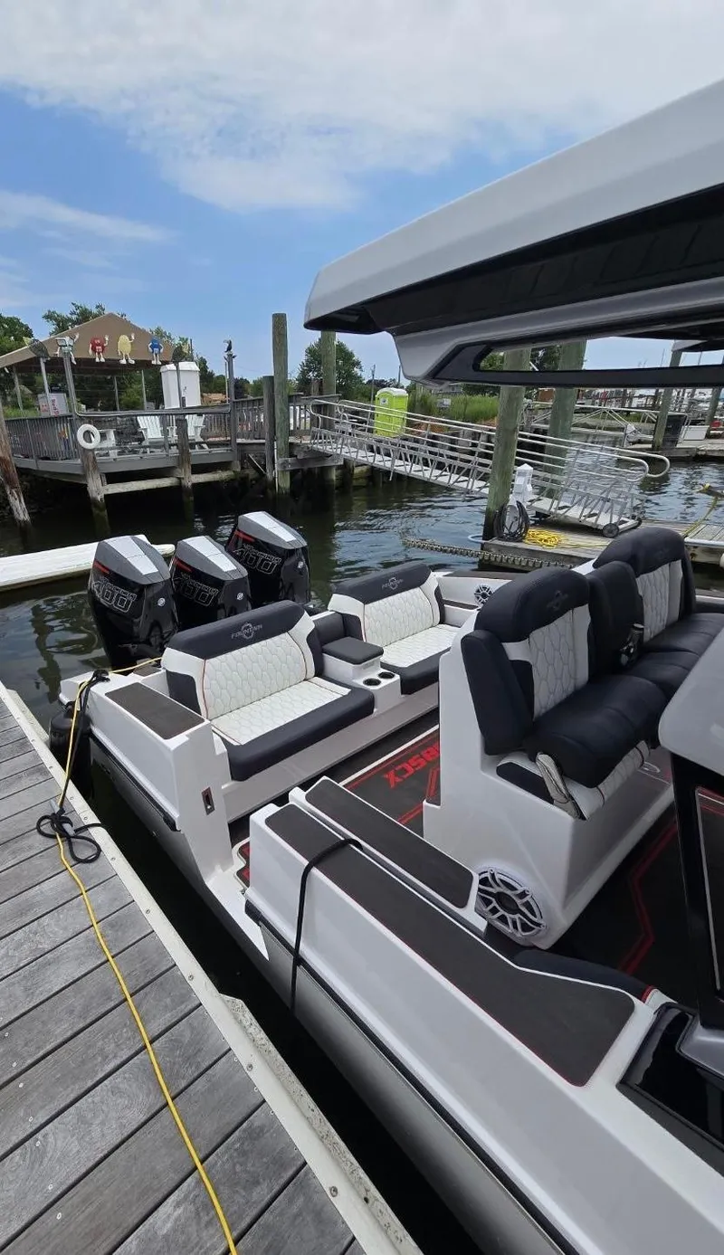 Slide: The Image of 2025 Fountain 38SCX boat docked, featuring sleek seating and triple outboard engines. - 12