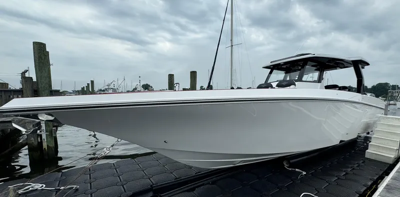 Slide: The Image of 2025 Fountain 38SCX boat docked under cloudy skies. - 2