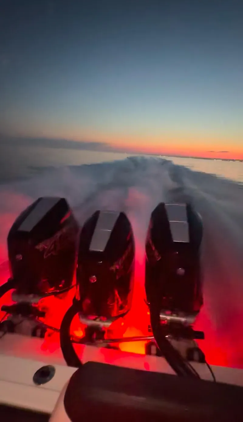 Slide: The Image of 2025 Fountain 38SCX boat with illuminated engines at sunset on the water. - 8