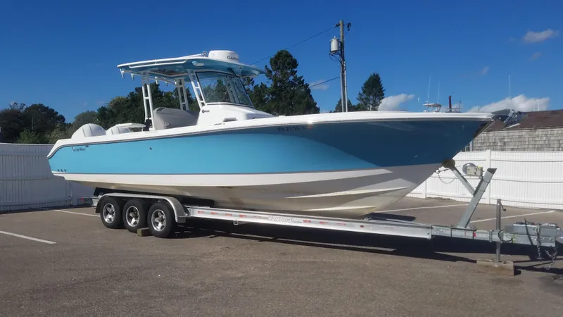 Slide: The Image of 2018 Edgewater 320 CC boat on trailer, parked outdoors under clear blue sky. - 0